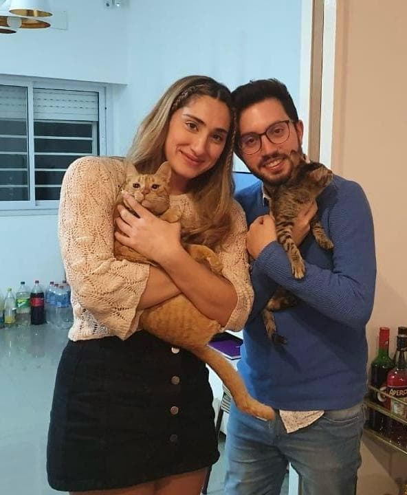 Juli y Luchi cada uno con un gato en brazos